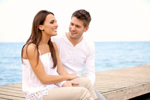 jeune couple souriant qui communique entre eux au bord de l'eau
